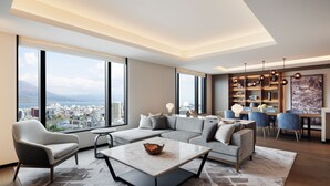 Una sala de estar moderna con un sofá modular, una mesa de centro y vistas a un paisaje urbano a través de amplios ventanales.