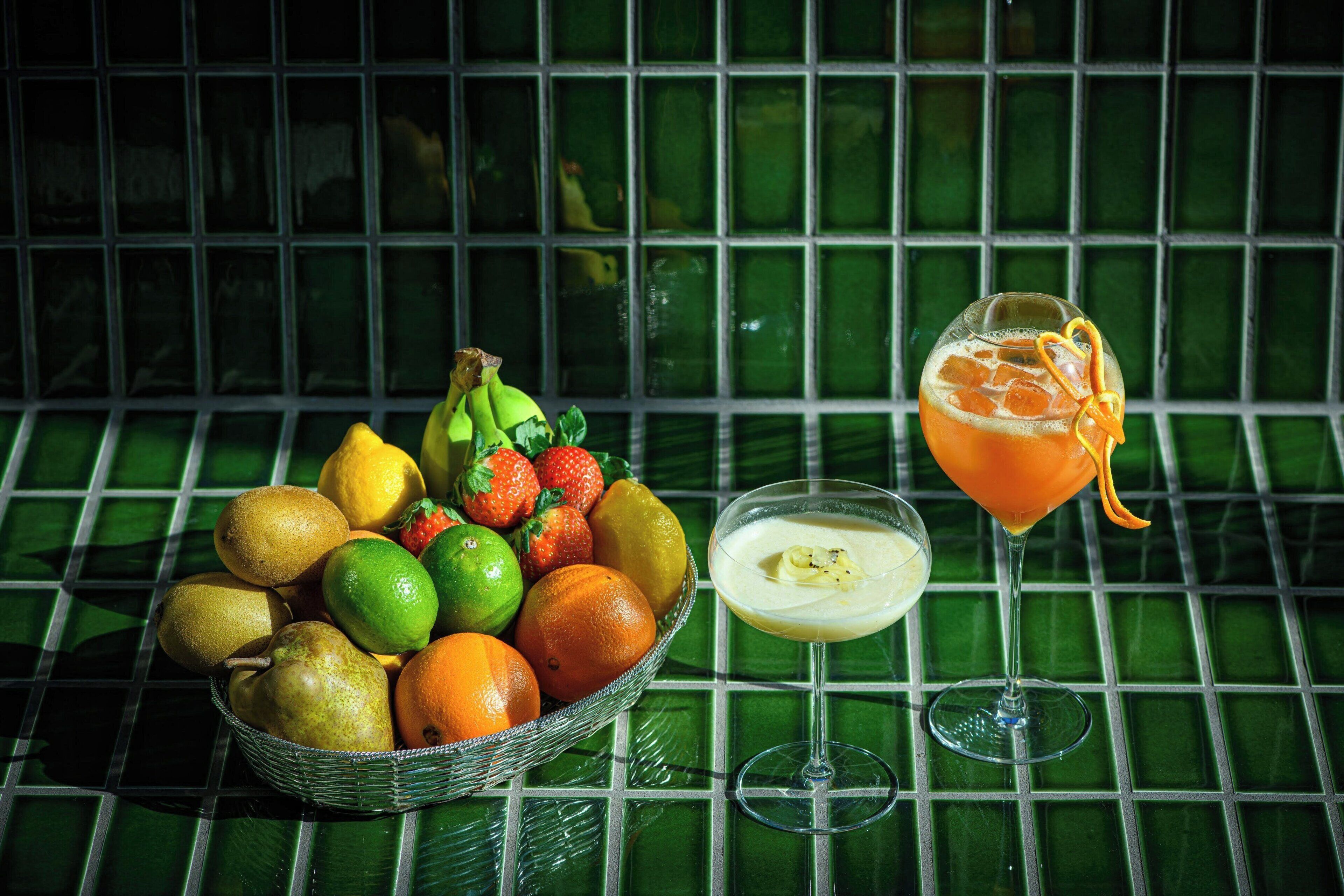 A table with a fruit basket and a cocktail glass.