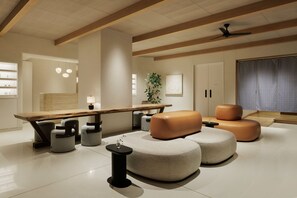 A modern living room with a wooden dining table, cushioned seating, and a ceiling fan.