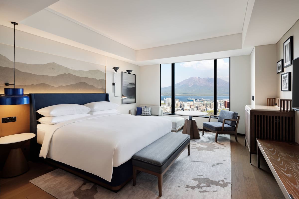 Ein modernes Hotelzimmer mit einem großen Bett, einer Sitzecke mit Blick und einem Esstisch.