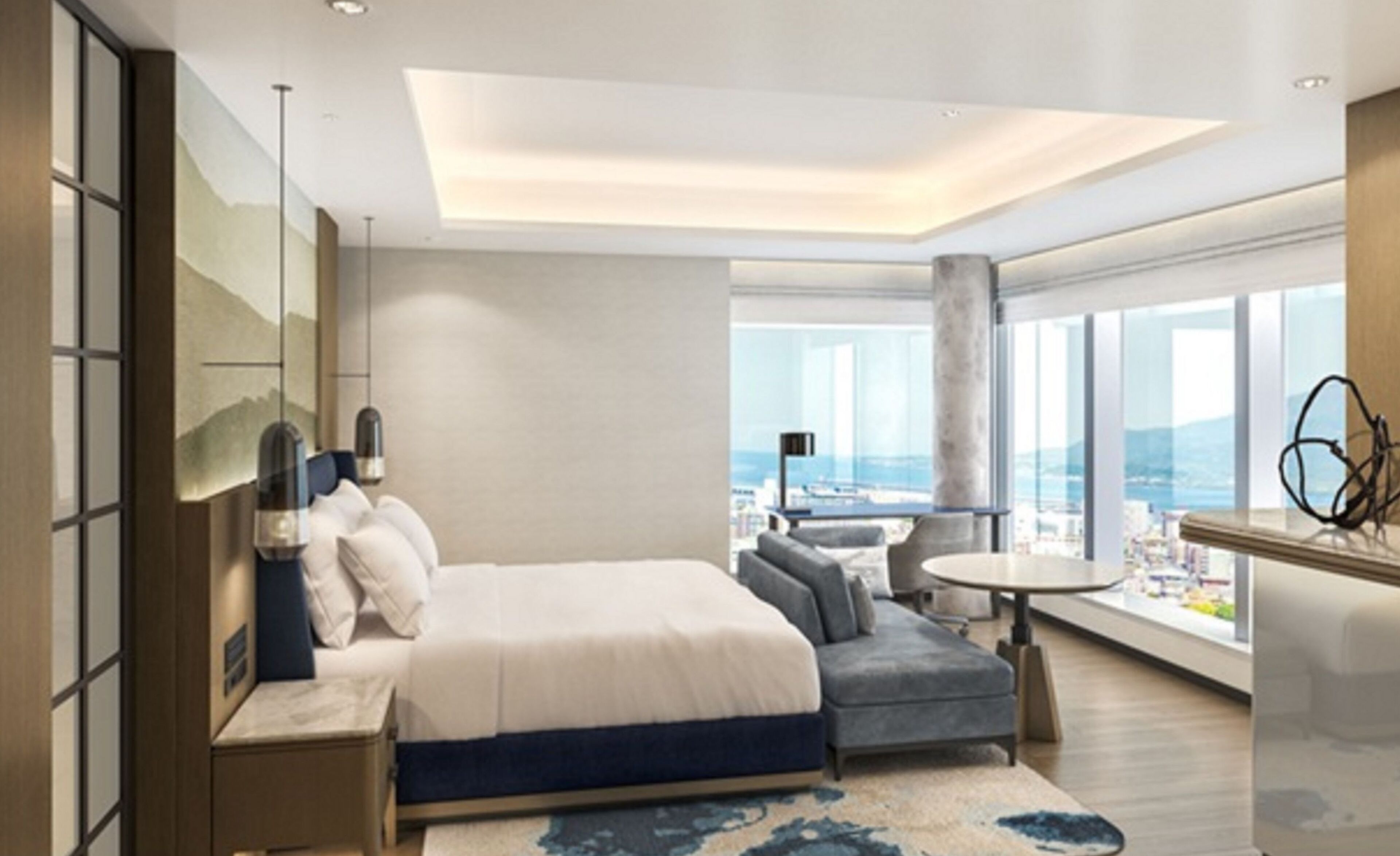 Habitación de hotel moderna con una cama grande, un sofá, una pequeña mesa redonda y vistas de la ciudad a través de amplios ventanales.