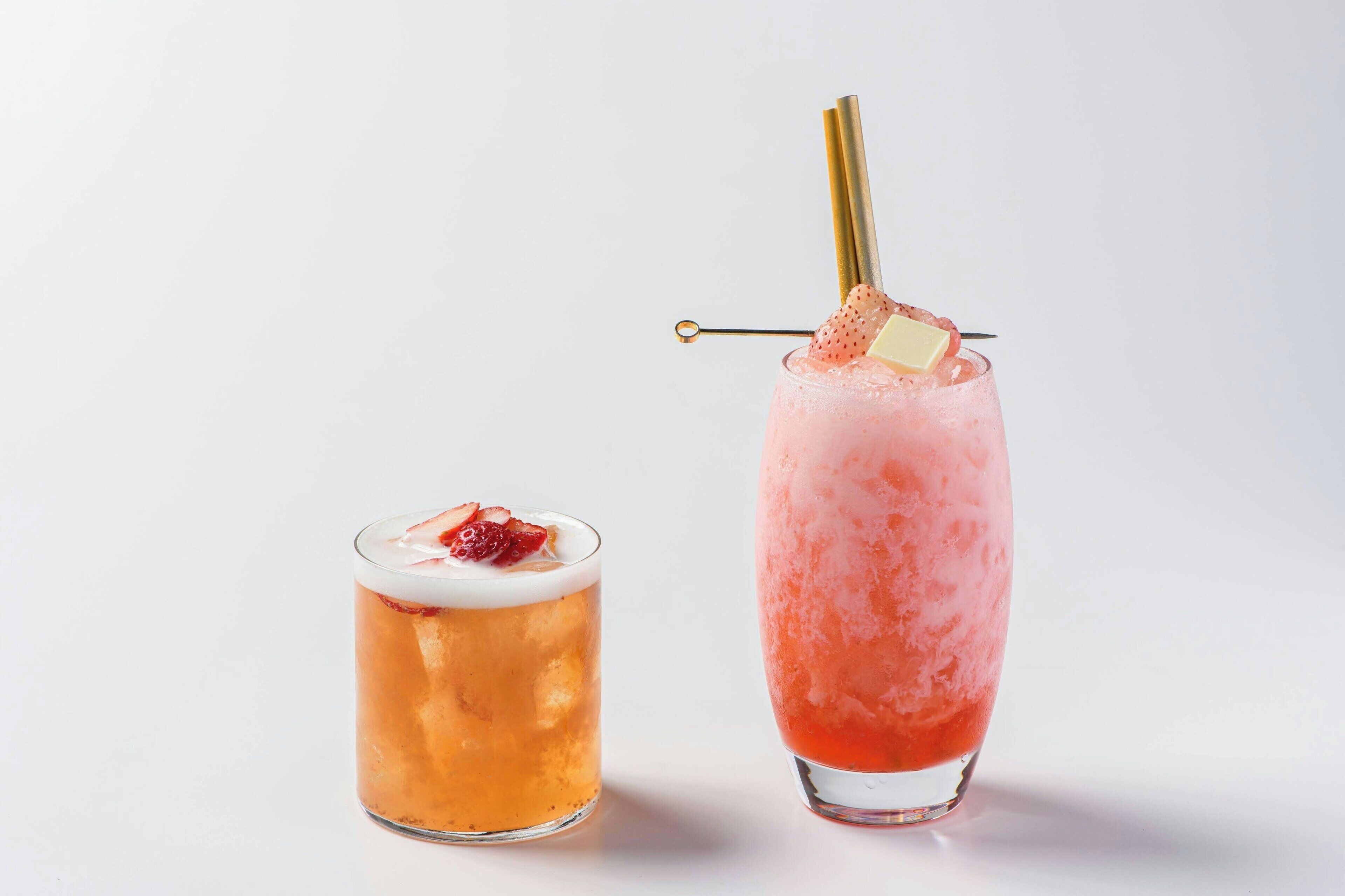 Two glasses of beverages, one with a straw and a slice of fruit, and the other with a straw and a slice of fruit.