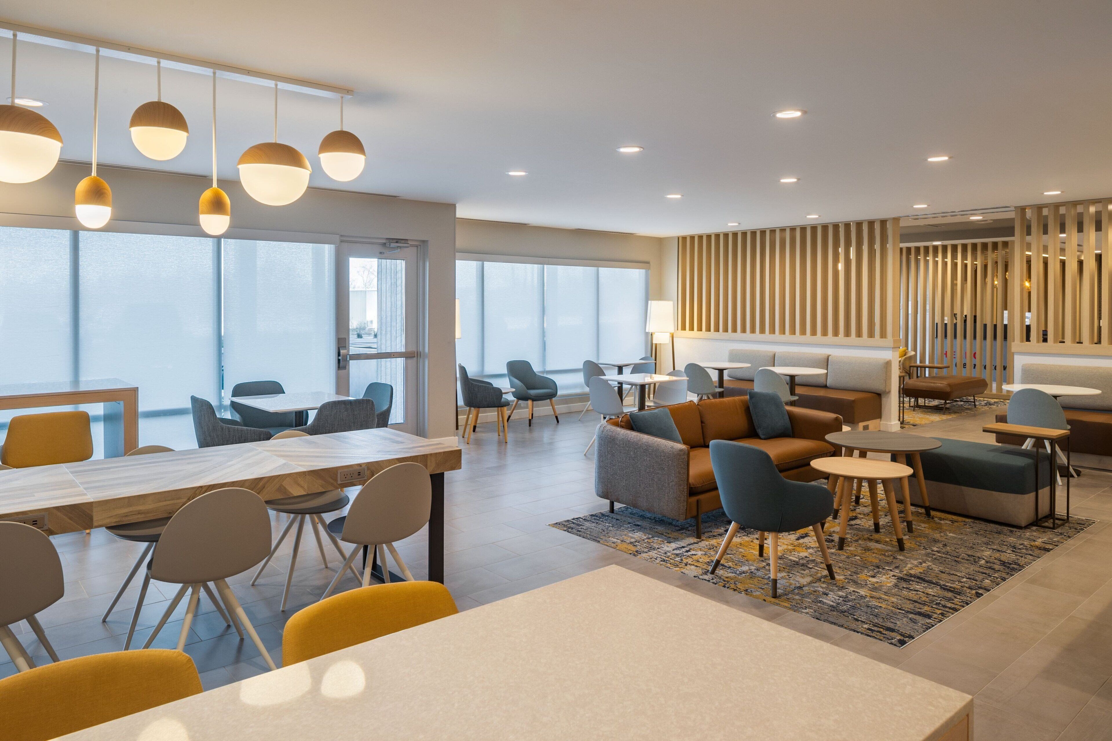 A modern hotel lobby with a long reception desk, comfortable seating areas, and large windows providing natural light.