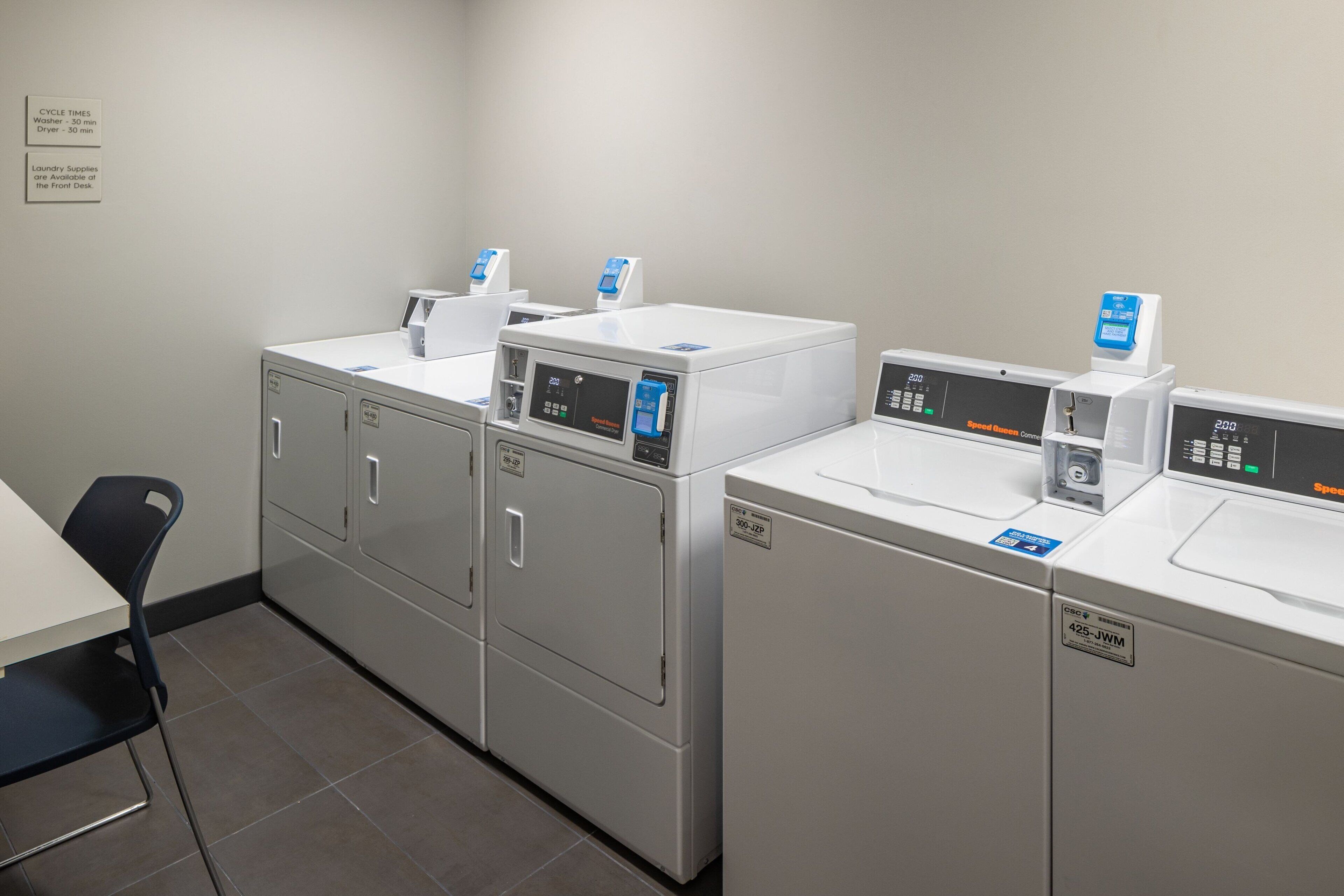 A laundry area with four washing machines and a table with chairs.