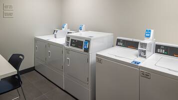 A laundry area with four washing machines and a table with chairs.