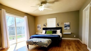A bedroom with a bed, a ceiling fan, and a large window.