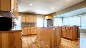 A spacious kitchen with wooden cabinets, a central island, and built-in appliances.