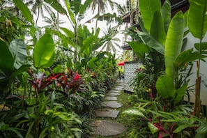 Stroll through the lush garden to our traditional building, featuring a red roof and surrounded by tropical plants.