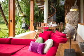 Relax in a serene outdoor space with a comfortable sofa and lush greenery.