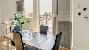 A dining area with a high ceiling, large windows, and a view of the outdoors.