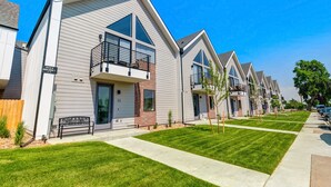 A row of modern townhouses with large windows, a balcony, and a well-maintained lawn.