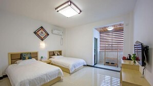 Habitación de hotel con dos camas, un escritorio, una silla, un televisor y una ventana con persianas.