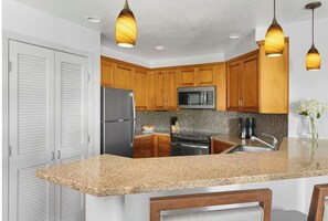 Enjoy cooking in this well-equipped kitchen with a granite countertop, wood cabinetry, and stainless steel appliances.