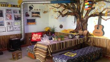 A cozy room with a tree mural, a guitar, and a bench.