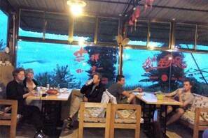 Um grupo de pessoas jantando em um restaurante ao ar livre, com vista para as montanhas.