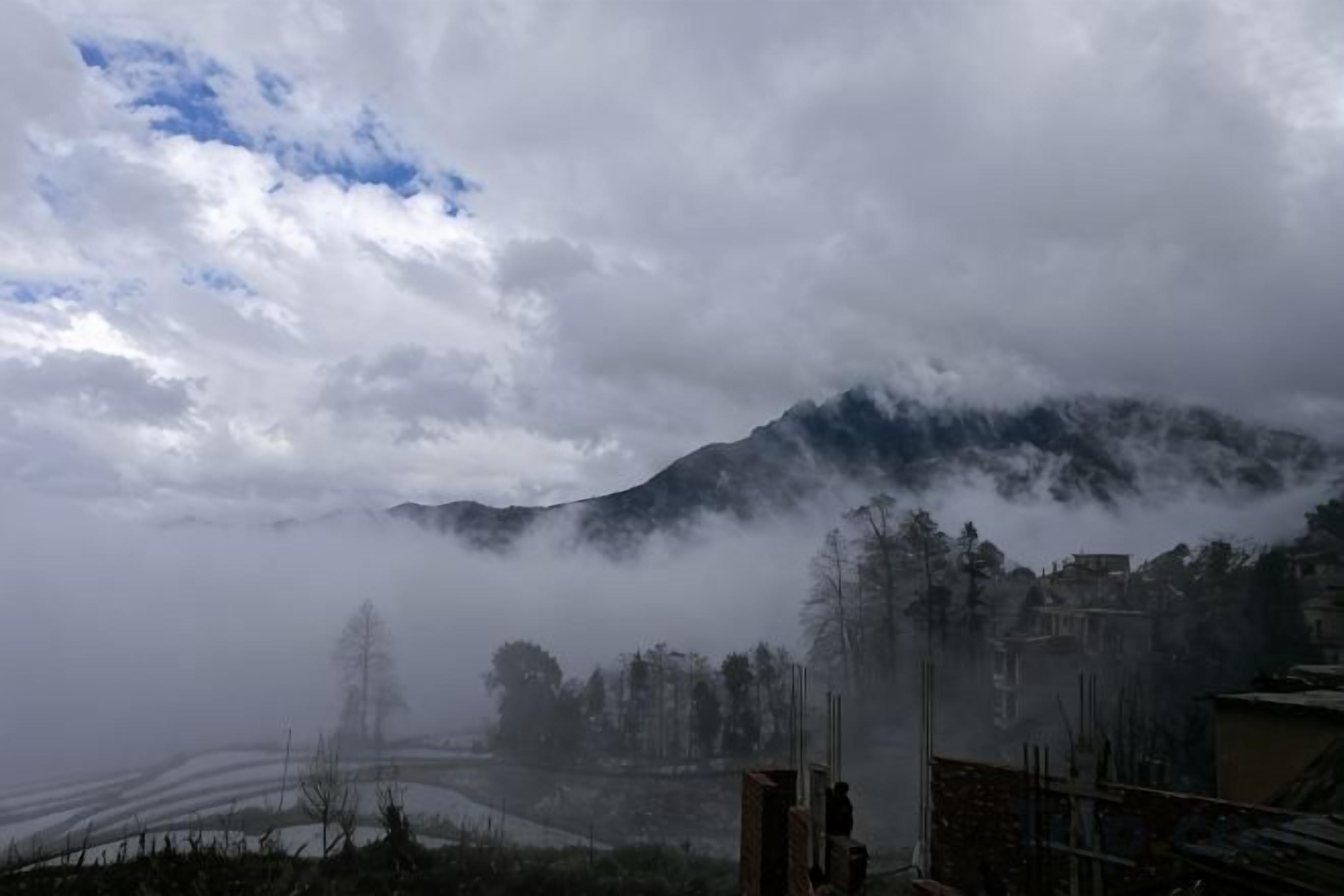 A mountainous landscape with a building in the foreground.
