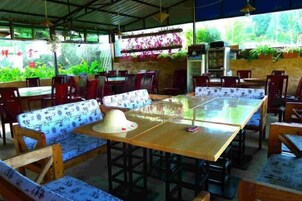Un comedor interior con mesas y sillas de madera, una mesa grande en el centro y un banco con estampado.