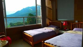 A bedroom with two beds, a window with a mountain view, a desk, and a chair.