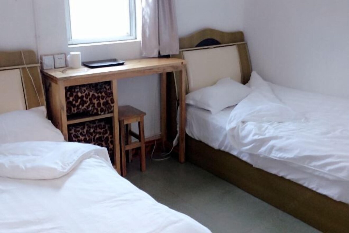 A bedroom with two beds, a desk, and a chair.