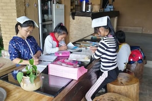 Un groupe de personnes est assis autour d’une table, devant des papiers, une plante et une boîte rose.
