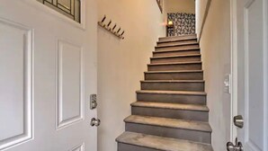 A staircase with a handrail, leading to a landing with a patterned wall.
