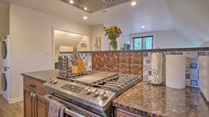 A kitchen with a stainless steel stove, wooden cabinets, and a tiled backsplash.