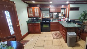 A kitchen with wooden cabinets, a microwave, an oven, a sink, and a trash bin.