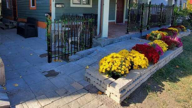 A two-story house with a porch, a front yard with a flower bed, and a mailbox.