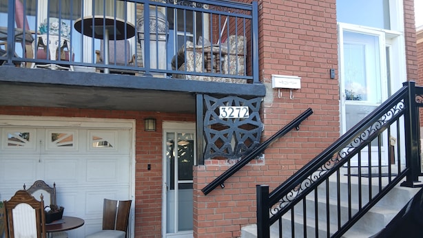 Un bâtiment à deux étages avec une façade en briques, une porte de garage blanche et un escalier en métal noir.