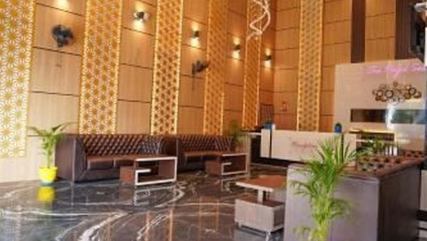 Un hall d’entrée moderne avec un sol en marbre, des lambris en bois, un comptoir d’accueil et des espaces aménagés pour s’asseoir.