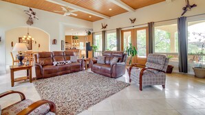 A spacious living room with leather sofas, a patterned rug, and large windows offering a view of the outdoors. - Luxe Lake Travis Vacation Rental w/ Heated Pool (Lago Vista)
