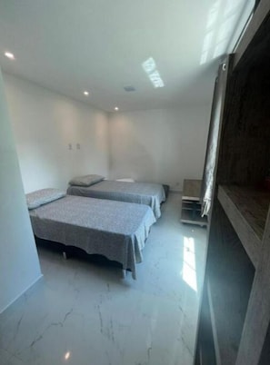 Une chambre avec trois lits, une armoire en bois et un sol en marbre.