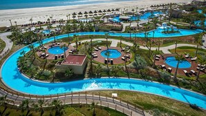 Un resort con múltiples piscinas, palmeras y vista al mar.