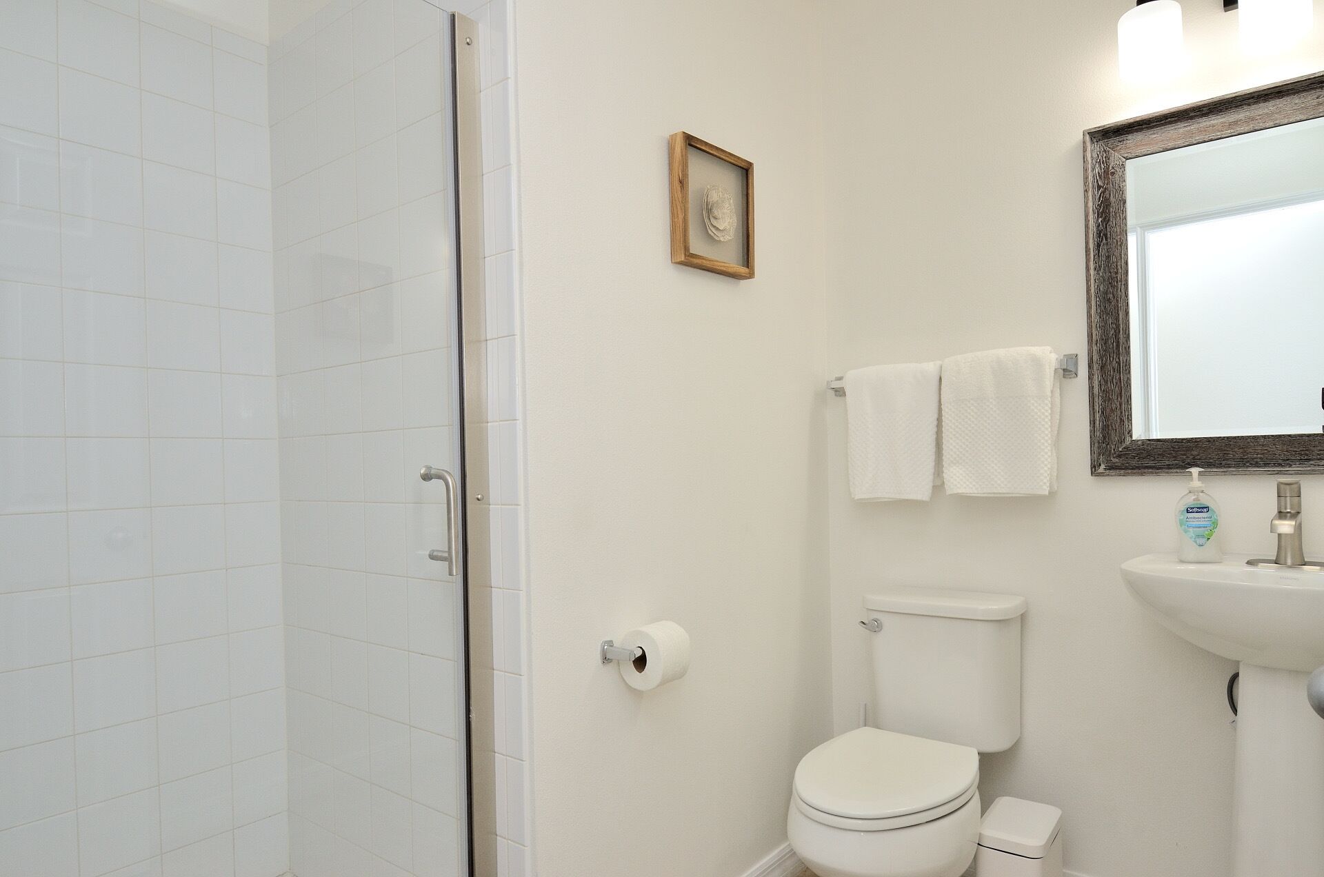 Une salle de bain avec des toilettes, un lavabo et un tableau encadré au mur.