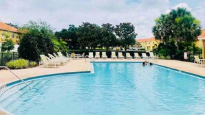 Une piscine avec des chaises longues et un ciel dégagé.