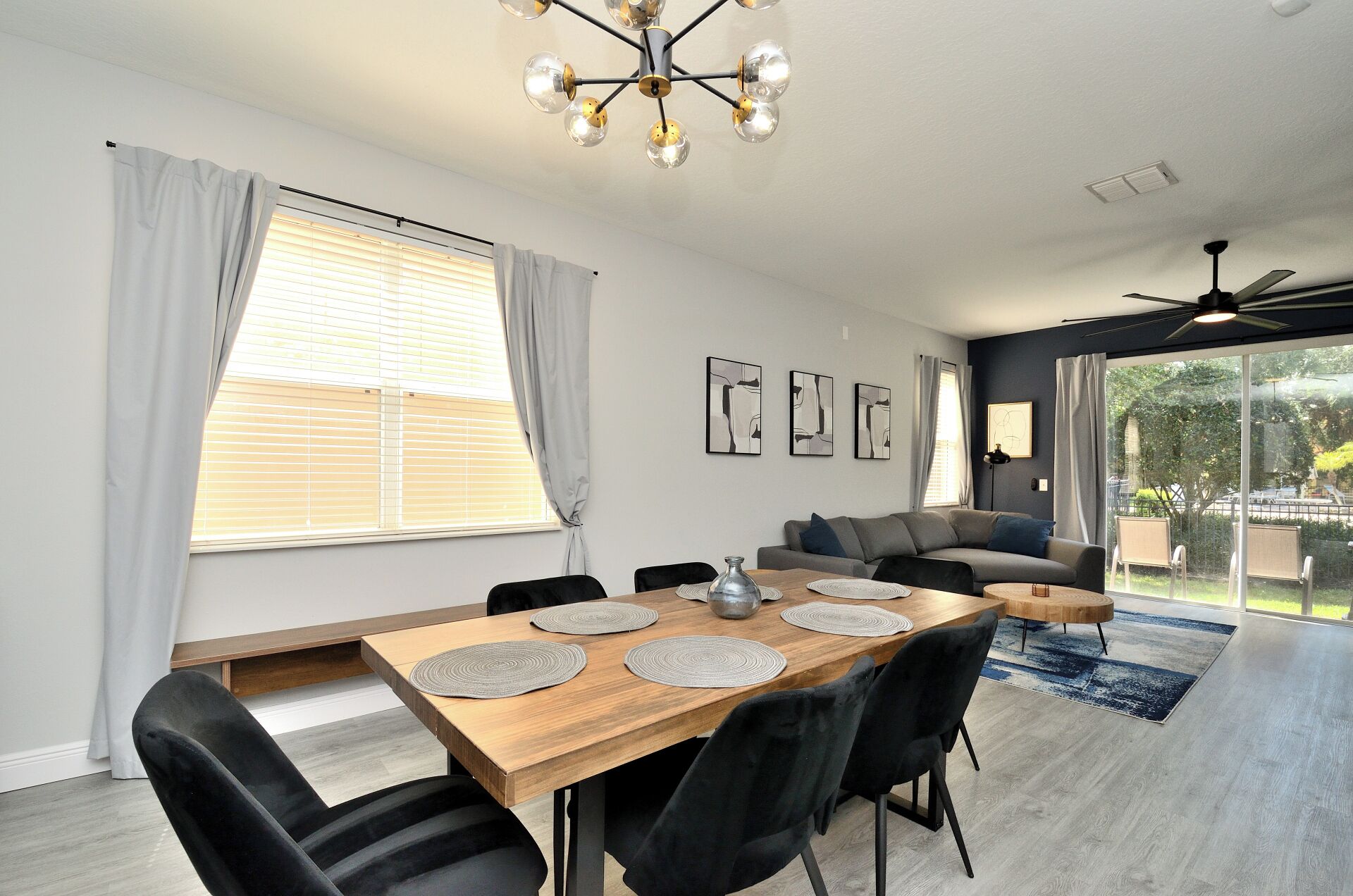 A modern dining area with a wooden table, black chairs, and a ceiling light fixture.