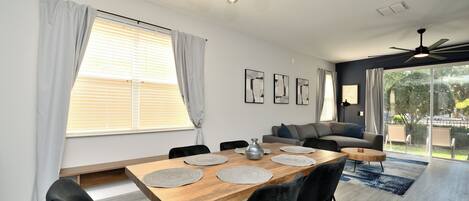 A modern dining area with a wooden table, black chairs, and a ceiling light fixture.