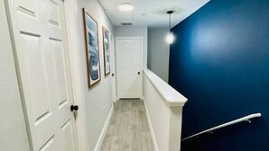 A hallway with white doors, framed pictures on the wall, and a blue accent wall. - Epic Disney Poolside Paradise,Disney 4miles, Universal 11miles, pool behind home (Kissimmee)