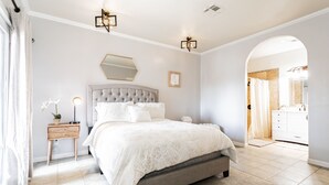 A bedroom with a large bed, a bedside table with a lamp, a mirror, and a view into the bathroom. - Cozy 2 bedroom apartment in Las Vegas (Las Vegas)