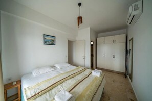 A bedroom with a bed, a wardrobe, and an air conditioning unit. - İlya Apart 1. (Bodrum)