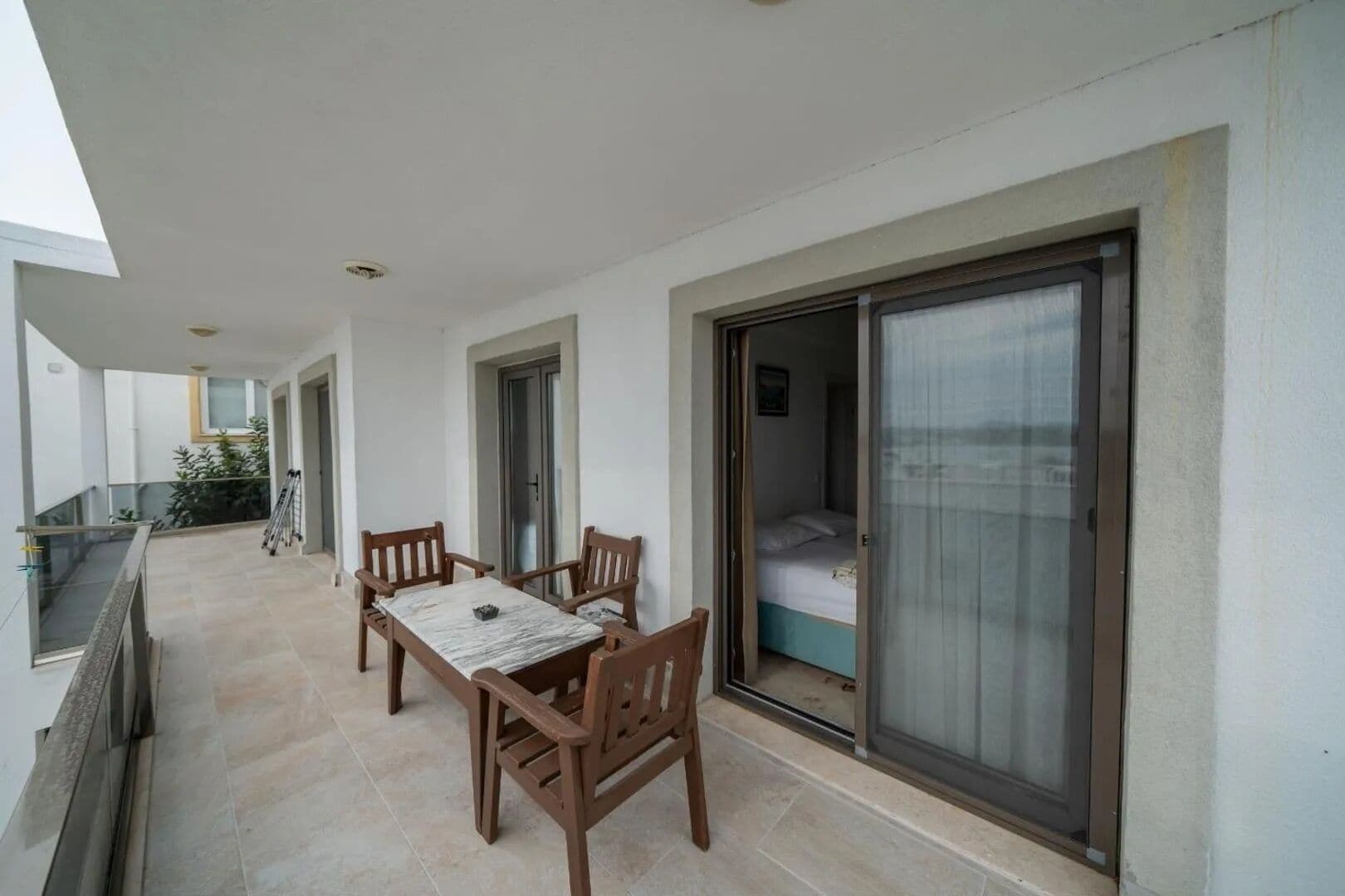 Een balkon met een tafel en stoelen, een schuifdeur naar een slaapkamer en uitzicht op de zee.