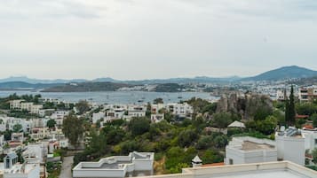 Une ville côtière aux bâtiments blancs, avec un promontoire rocheux et une vue sur la mer, où l’on peut apercevoir des bateaux.