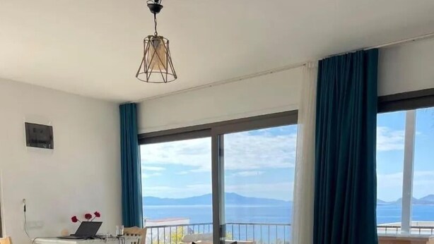 Una sala moderna con un sofá modular, una mesita blanca y un balcón con vistas al mar.