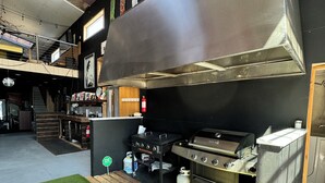 A commercial kitchen with stainless steel appliances, a fire extinguisher, and a Blackstone grill cart. - Amazing repurposed grain elevator! (Sabin)