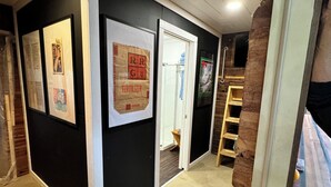 A hallway with black walls, white trim, and a carpeted floor. There are framed pictures and a sign on the wall. A wooden ladder is leaning against the wall. - Amazing repurposed grain elevator! (Sabin)