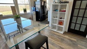 A modern kitchen with a glass dining table, a black refrigerator, and a white shelving unit with toys. - Amazing repurposed grain elevator! (Sabin)
