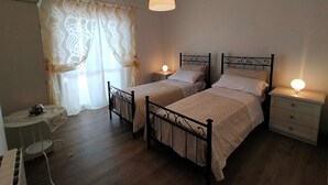 Une chambre avec deux lits simples, un petit bureau et une chaise.