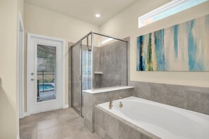A modern bathroom with a glass-enclosed shower, a large bathtub, and a view of a pool through a door.