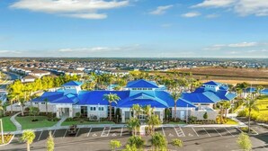 A large hotel with multiple blue-roofed buildings, a parking lot, and surrounding greenery. - Magical Themed Villa in Windsor Isalnd (Davenport)