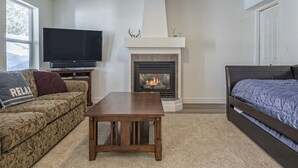 Una sala de estar con chimenea, sofá, televisor y cama.
